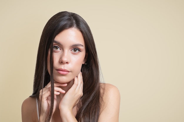 Retrato da beleza de uma jovem morena em um fundo bege.