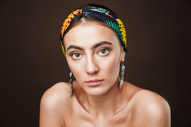 Retrato da beleza de uma jovem mulher bonita em topless usando bandana e brincos isolados