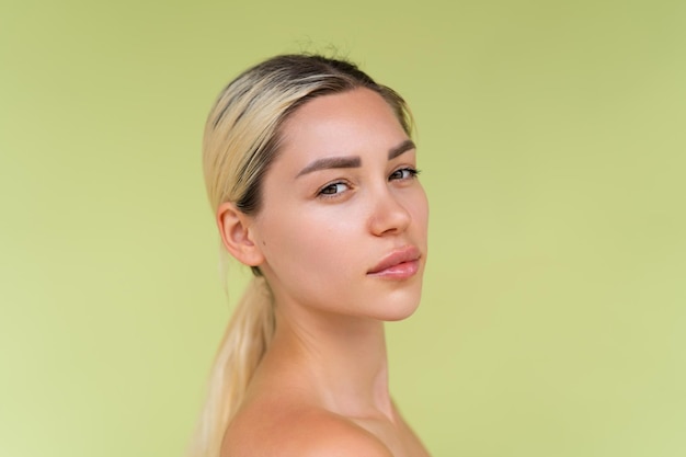 Retrato da beleza de uma jovem mulher em topless com ombros nus sobre fundo verde com pele perfeita e maquiagem natural