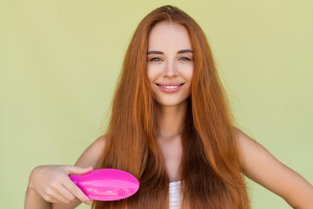 Retrato da beleza de uma jovem ruiva sem camisa com ombros nus em pincel de fundo verde, cabelos longos, fortes e brilhantes