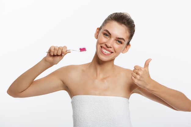 Retrato da beleza de uma linda mulher seminua feliz escovando os dentes com uma escova de dentes e looki