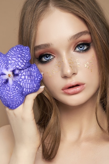 Retrato da beleza de uma mulher com um vanda orchid azul na mão.