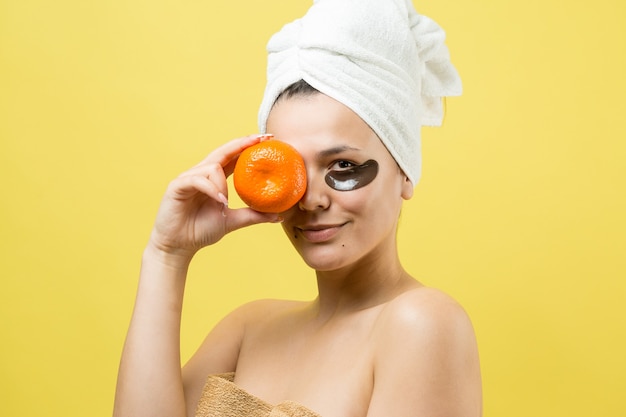 Retrato da beleza de uma mulher com uma toalha branca na cabeça e uma máscara nutritiva de ouro no rosto