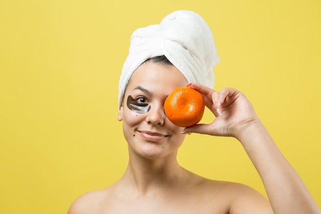 Retrato da beleza de uma mulher com uma toalha branca na cabeça e uma máscara nutritiva de ouro no rosto