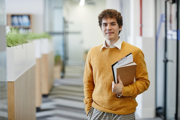 Retrato da cintura para cima de um jovem no escritório olhando para a câmera, novo funcionário e espaço de cópia do conceito de estágio