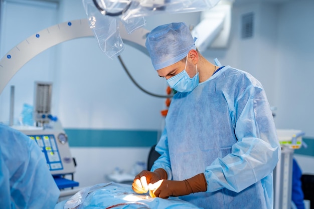 Retrato da cintura para cima do jovem assistente caucasiano masculino ou estagiário usando máscara facial médica em pé na enfermaria médica e se preparando para a operação Equipamento na mesa de operação