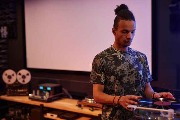 Retrato da cintura para cima do jovem negro tocando discos de vinil contra o espaço da cópia da tela do projetor