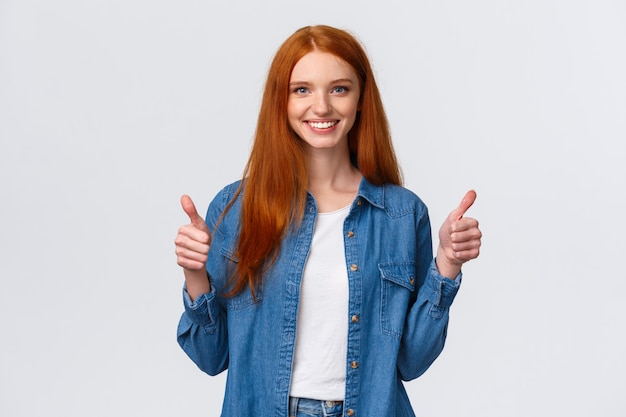 Retrato da cintura para cima sedutor confiante sorridente ruiva blogueiro rever novo produto impressionante, mostrando os polegares para cima em aprovação, como ou concordar gesto