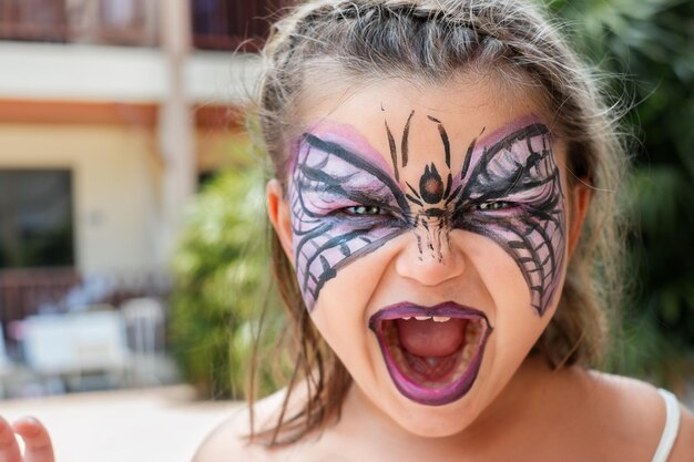 Retrato da criança com máscara de desenho de Halloween no rosto ao ar livre