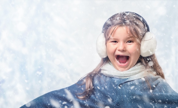 Retrato da criança feliz e sorridente na neve no inverno