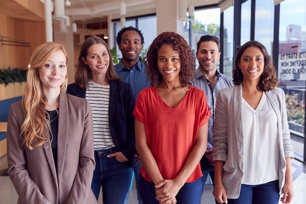 Retrato da equipe de negócios multiculturais em pé no escritório moderno de plano aberto juntos