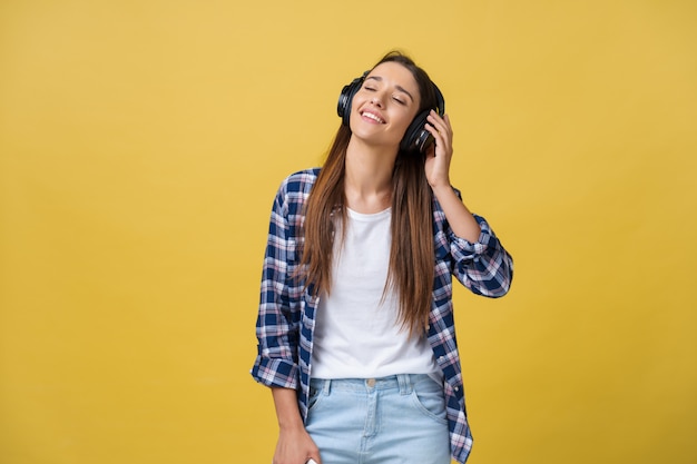 Retrato da escuta alegre da mulher caucasiano bonita a música no telefone móvel.