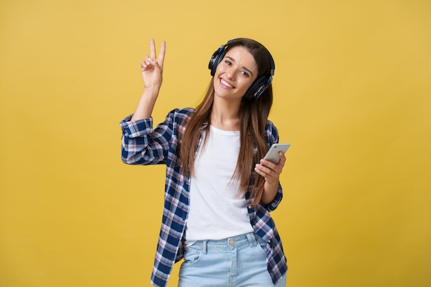 Retrato da escuta alegre da mulher caucasiano bonita a música no telefone móvel.