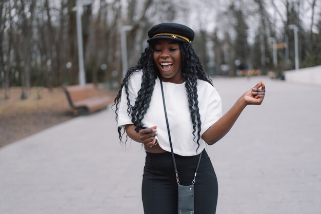 Retrato da foto de alegre garota de pele negra. Garota afro dança no parque da cidade.