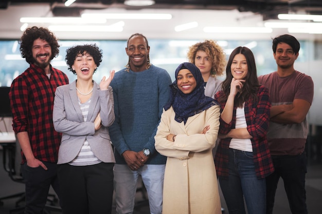 retrato da jovem equipe de negócios multiétnica animada de desenvolvedores de software em pé e olhando para a câmera enquanto comemora o sucesso no escritório de inicialização moderno