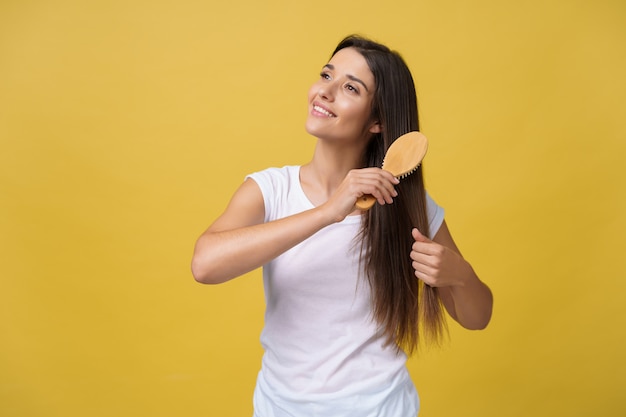Retrato da jovem mulher bonita que penteia seu cabelo, olhando a câmera e o sorriso.