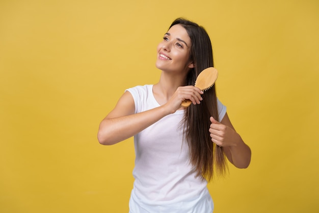 Foto retrato da jovem mulher bonita que penteia seu cabelo, olhando a câmera e o sorriso.