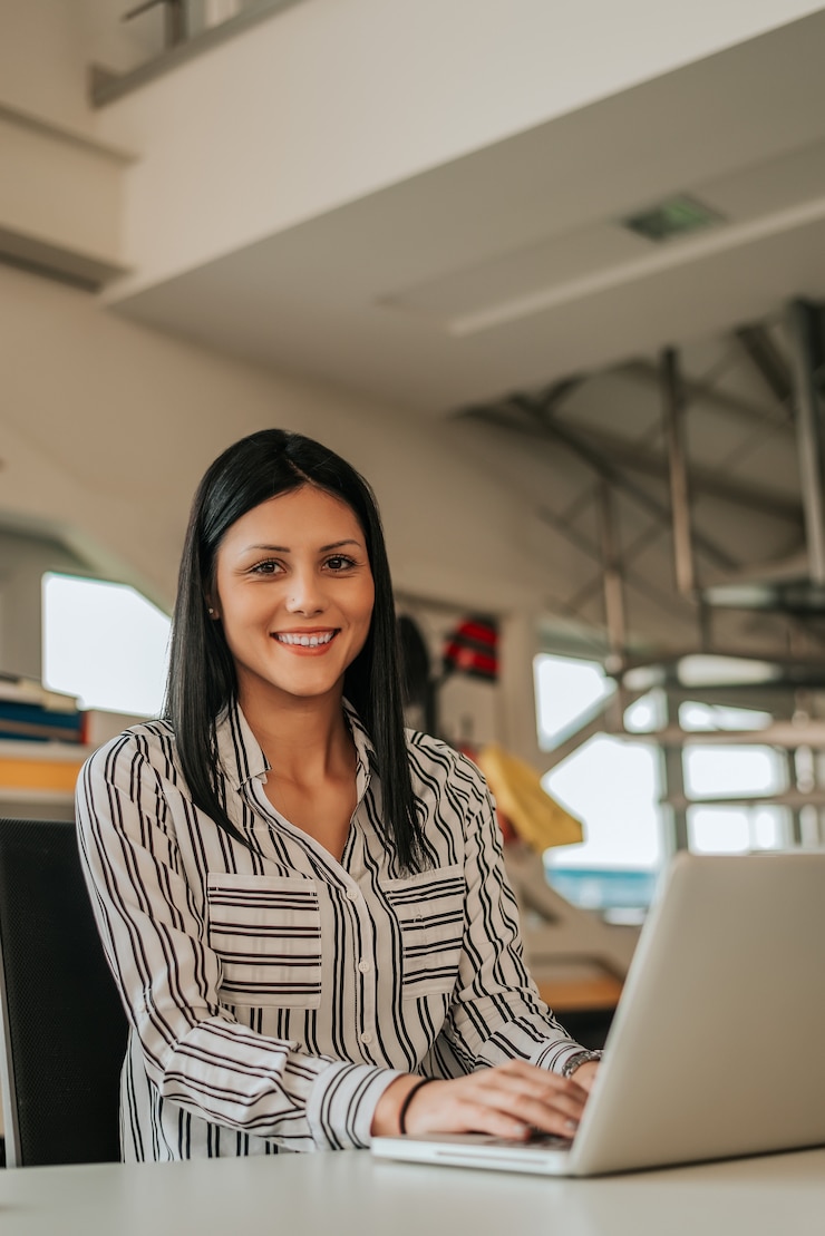 Foto retrato da jovem mulher no local de trabalho com portátil.