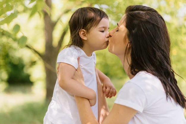 Retrato da linda mãe caucasiana e seu filho fofo brincando ao ar livre abraçados e dar um beijo Linda mulher e sua filha aproveitam o tempo juntos no parque Maternidade de pessoas