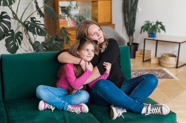 Retrato da linda mãe de duas pessoas e seu abraço de criança. Eles passam o tempo livre juntos, sentam-se em um confortável divã dentro de casa. Conceito de família.