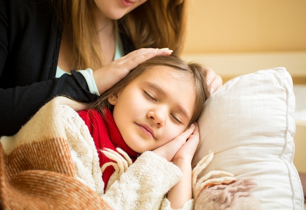 Foto retrato da mãe segurando a mão na cabeça da filha adormecida