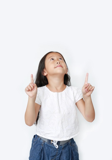 Retrato da menina asiática da criança pequena que aponta o dedo indicador dois acima e que olha isolado acima.