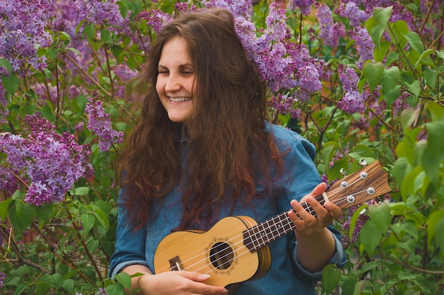 Retrato da menina bonita com cabelo encaracolado tocando o ukulele