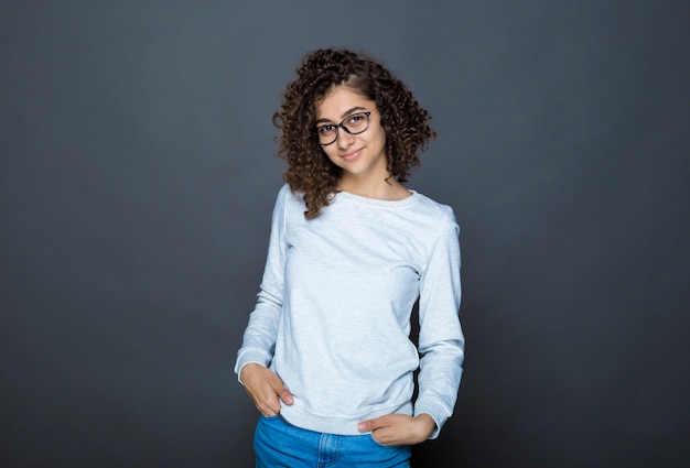 Retrato da menina moreno de sorriso indiana nos vidros em um preto. Estudante Feminina. Adolescente