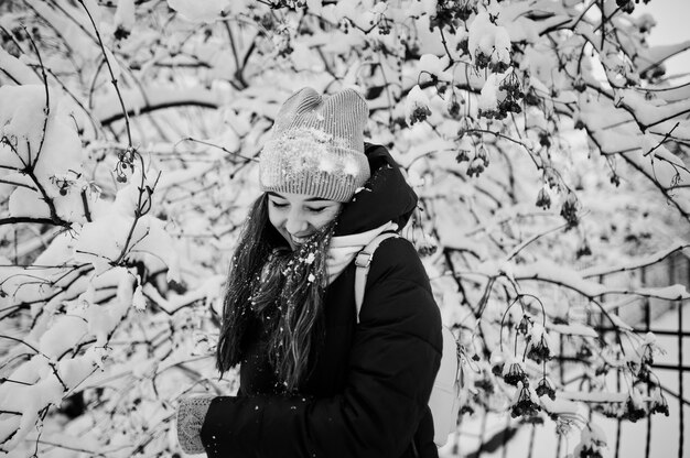 Retrato da menina no dia nevado do inverno perto das árvores cobertos de neve.