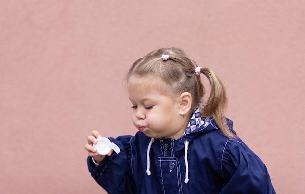 Retrato da menina soprando bolhas de sabão no fundo rosa