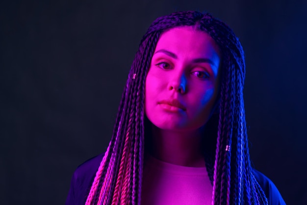 Foto retrato da moda de jovem com dreadlocks em luz de néon