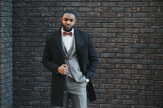 Retrato da moda de um jovem homem de negócios afro-americano caminhando ao ar livre em uma pose casual
