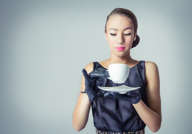 Retrato da moda de uma linda jovem com uma xícara de café em estilo vintage clássico