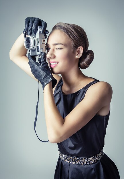 Retrato da moda de uma linda jovem em estilo vintage clássico com uma câmera fotográfica analógica