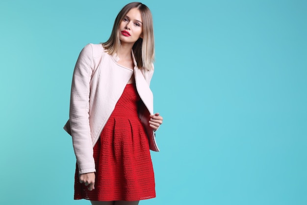 Retrato da moda jovem de jaqueta de couro rosa e vestido vermelho. Fundo turquesa, foto do estúdio