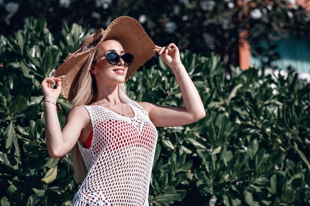 Retrato da moda. mulher loira sorridente com aparência elegante. estilo do mar. no fundo da natureza. estilo e garota gostosa ao ar livre. mulher de óculos de sol e chapéu de palha. moda.