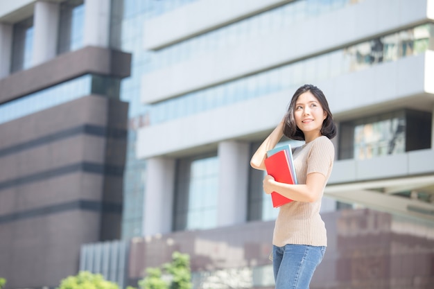 Retrato da mulher asiática atrativa do estudante que está no lugar exterior.