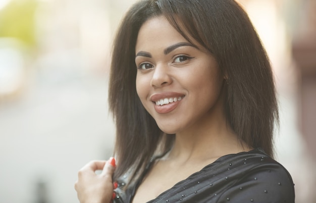 Retrato da mulher negra nova de sorriso ao ar livre.