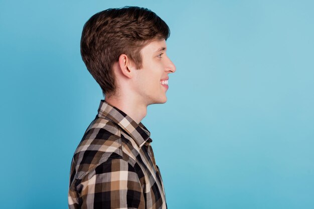 Retrato da vista lateral do perfil de um jovem alegre de bom humor, olhar o espaço vazio isolado sobre o fundo de cor azul