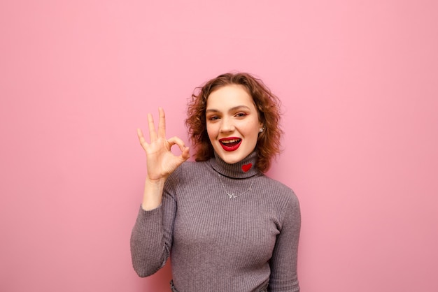 Retrato de dama bonita feliz en suéter gris y pelo rizado