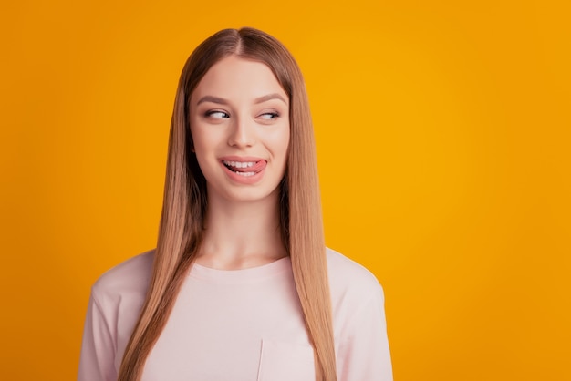 Retrato de dama de ensueño coqueta mostrar mirada de lengua lado espacio vacío cara astuta sobre fondo amarillo