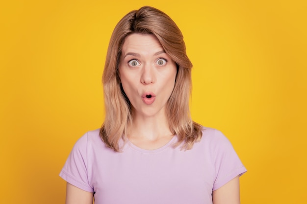 Retrato de dama graciosa sorprendida mira la cámara boca abierta reacción omg sobre fondo amarillo