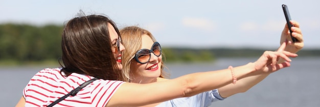 Retrato das melhores amigas tirando uma linda selfie no smartphone sorrindo lindas mulheres brilhantes