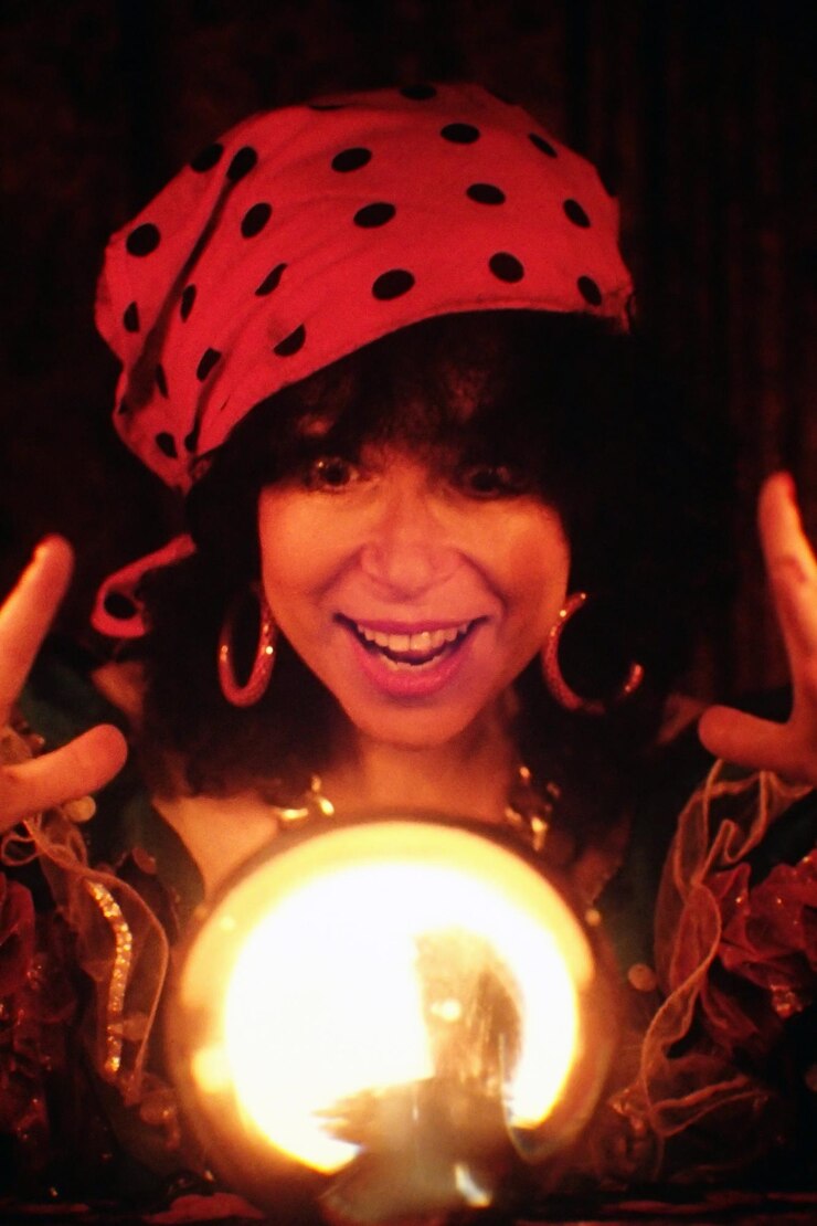 Foto retrato de adivinha sorridente com bola de cristal iluminada na sala escura
