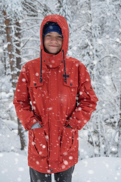 Retrato de adolescente andando e se divertindo na floresta de inverno nevando