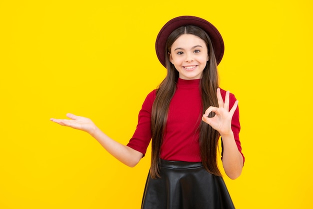 Retrato de adolescente feliz Retrato aproximado dela, ela é uma garota bonita e atraente alegre espantada apontando de lado no espaço da cópia isolado em fundo amarelo Garota sorridente