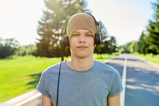 Retrato de adolescente hipster com chapéu de malha com fones de ouvido olhando na câmera