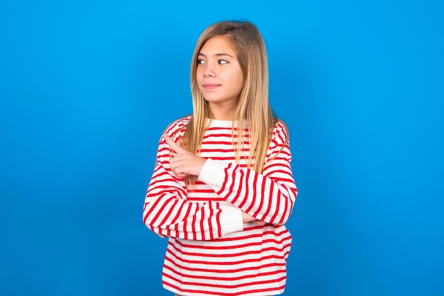 Retrato de adolescente posando para a câmera com aparência complicada, apresentando o produto com o dedo indicador