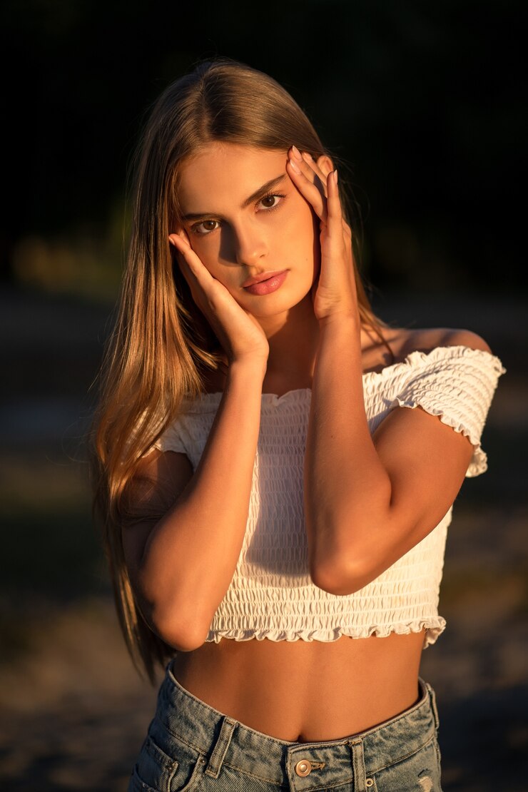 Foto retrato de adolescente tocando seu rosto com as palmas das mãos. jovem caucasiana posando no pôr do sol na natureza. conceito de cuidados com a pele. conceito de beleza.