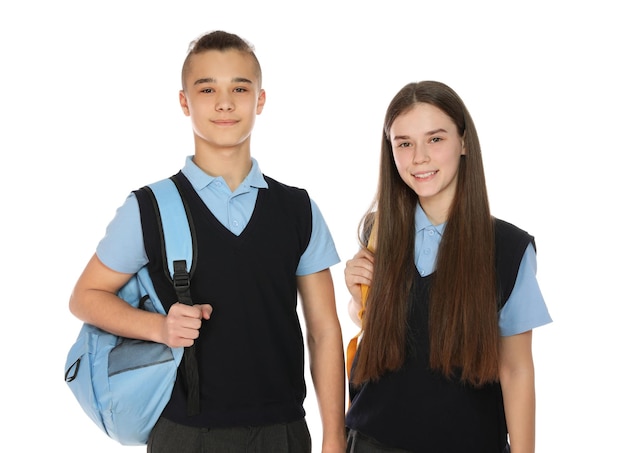 Retrato de adolescentes em uniforme escolar com mochilas em fundo branco